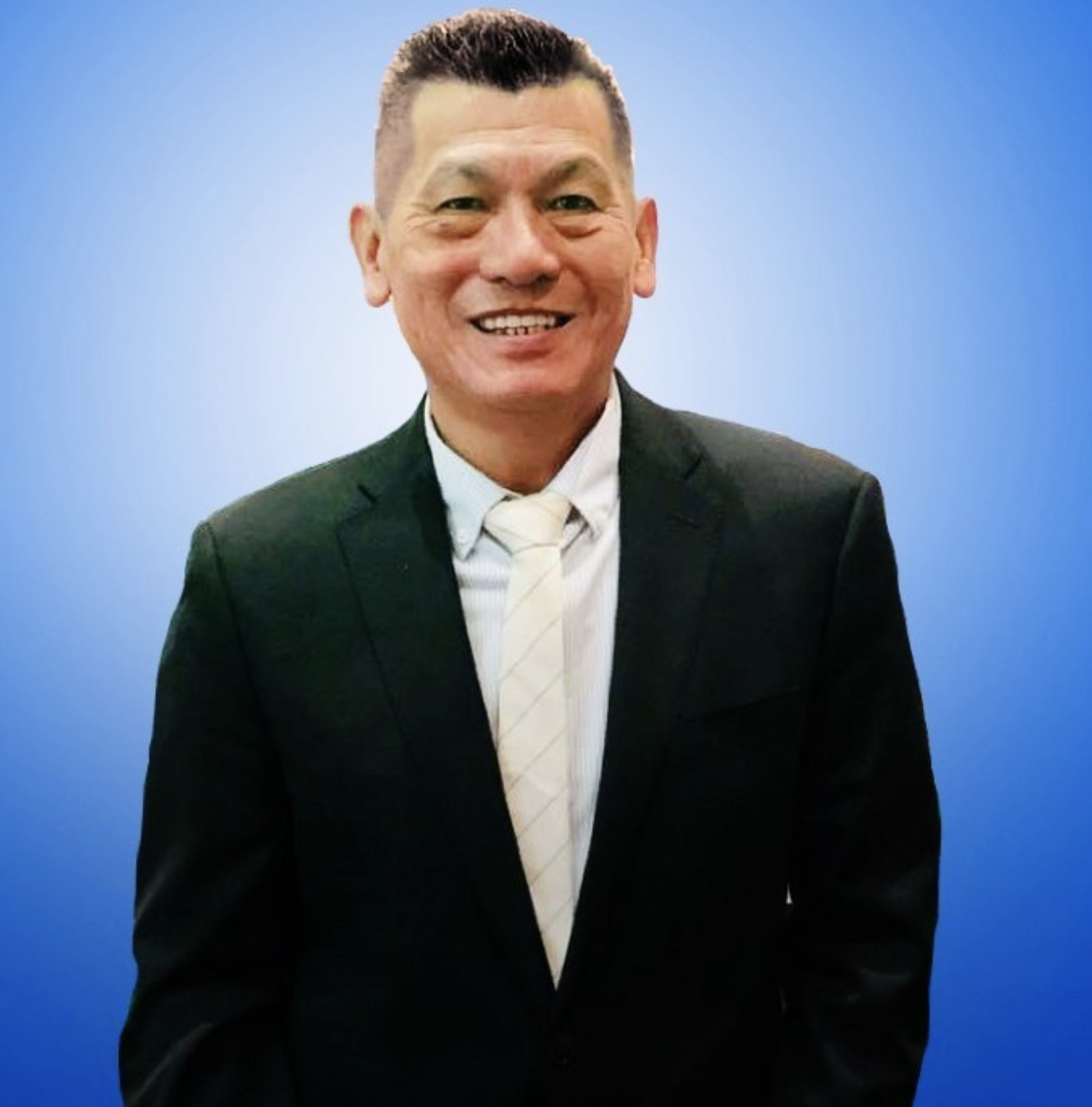 A photo of CFO Norman Son Kee, smiling, wearing a black suit, and standing in front of a blue background.